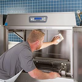 Man with an apron cleaning a  Hobart commercial dishwasher