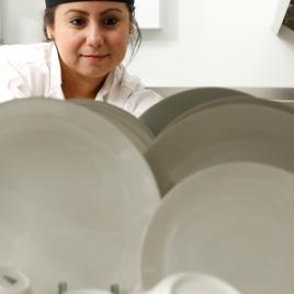Restaurant employee looking over a shelf of clean white dishes